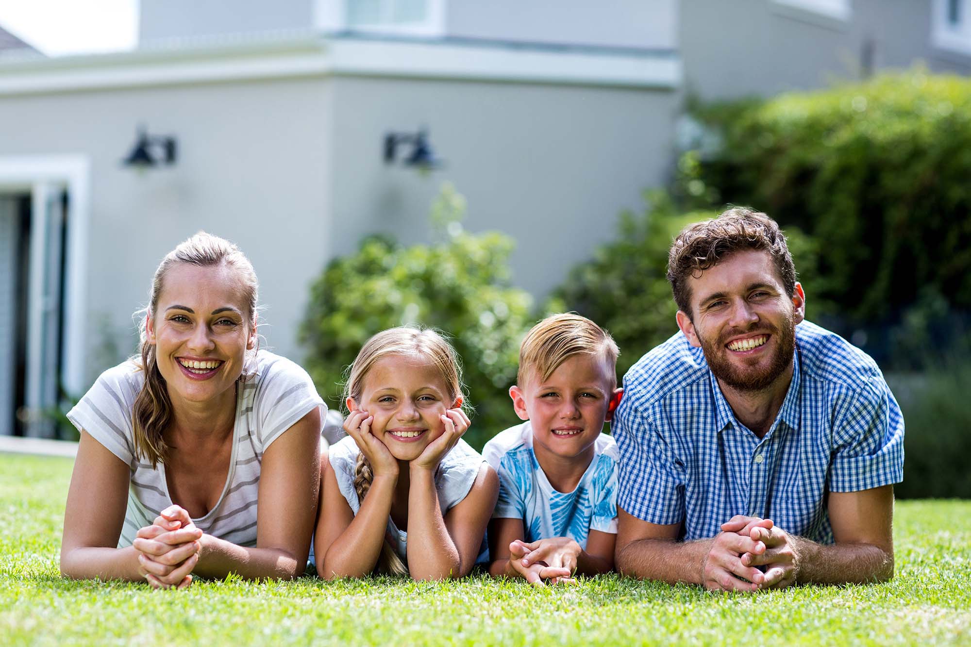 Front view of happy family lying in yard